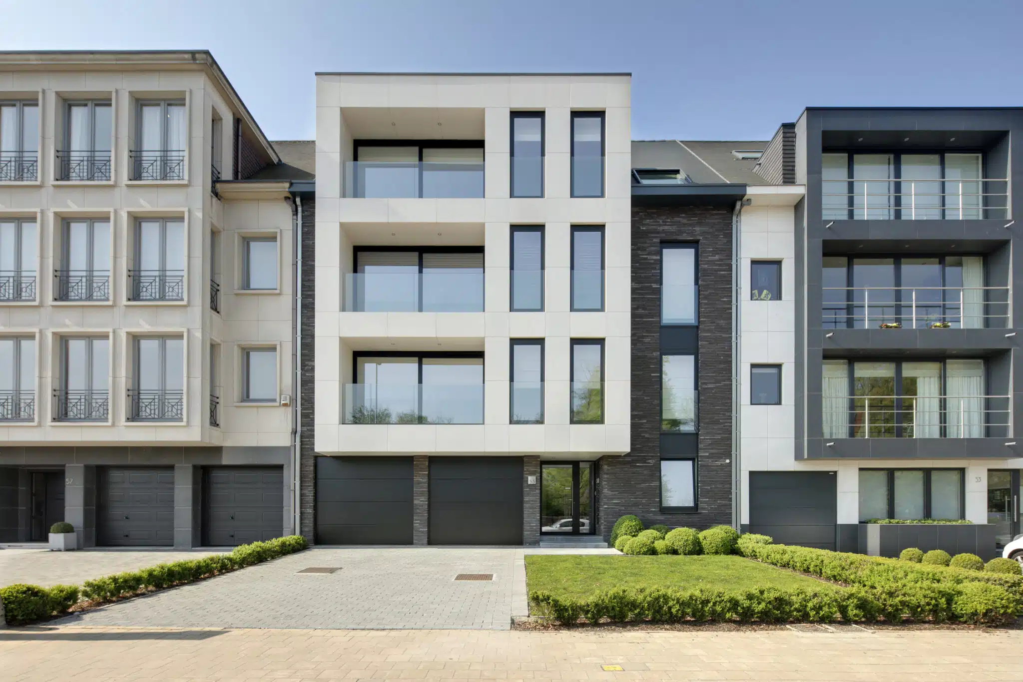Moderne appartementsgebouwen met glazen balkons en donkere gevelbekleding in Sint-Niklaas, ontworpen door ONA Architecten Bev