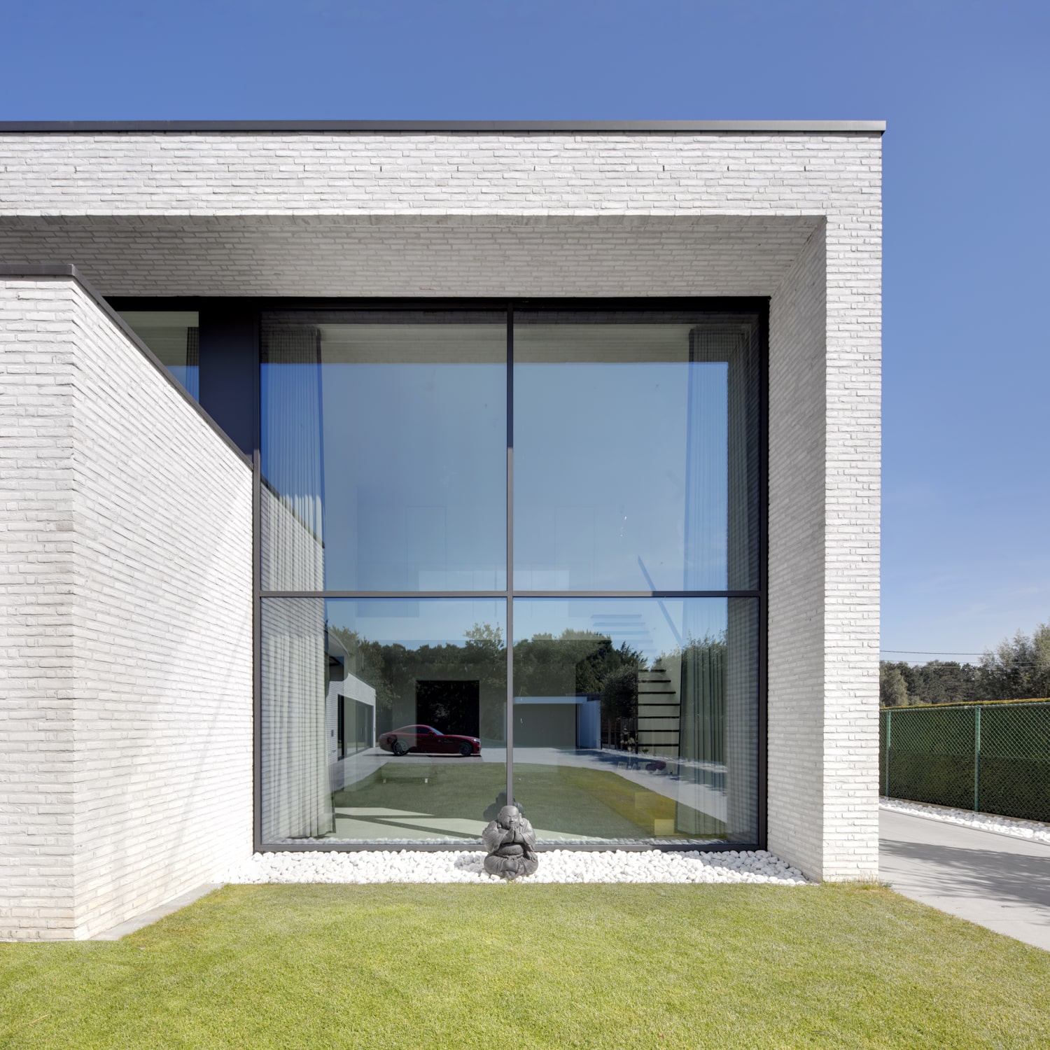 Moderne nieuwbouw woning Stekene met witte bakstenen gevel en grote glazen raampartij, ontworpen door ONA Architecten – Prive