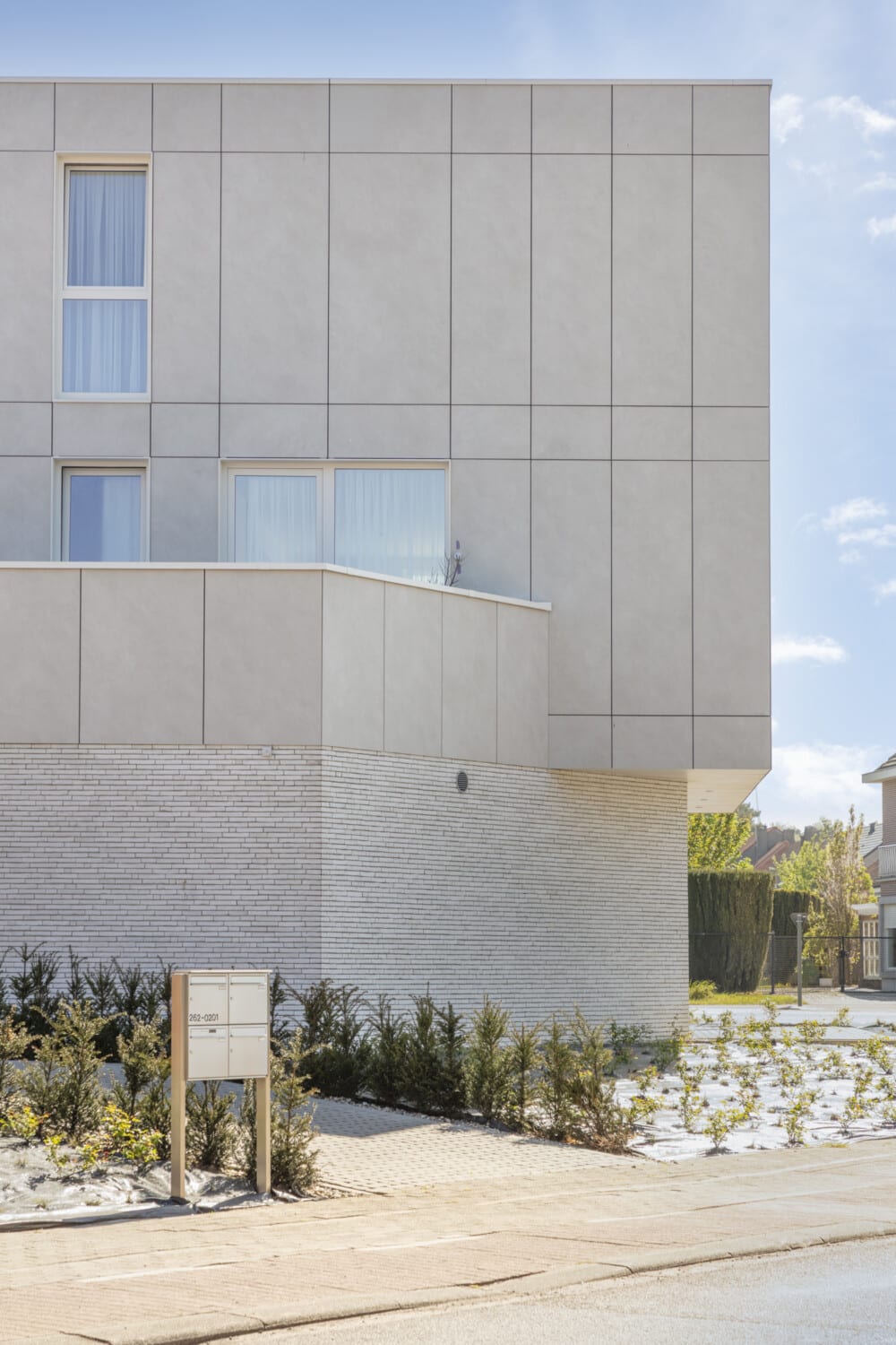Moderne nieuwbouwwoning Ster in St-Niklaas met lichte gevelpanelen, witte baksteen en brievenbussen vooraan — ONA Architecten