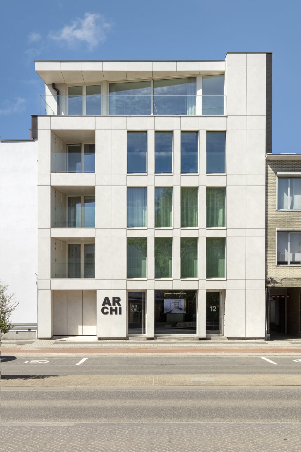 Gevel van kantoor ONA Architecten in Beveren, modern wit gebouw met grote raampartijen, glazen balustrades en ARCHI-opschrift