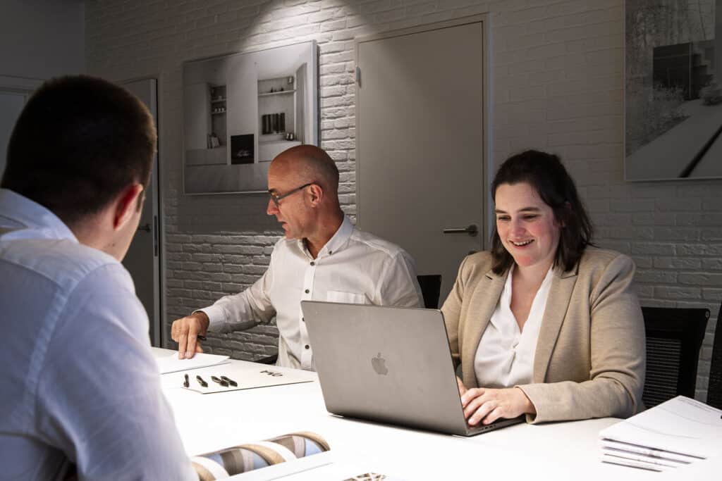 Architecten van ONA Architectenbureau Beveren in overleg met een klant aan tafel, met laptop en plannen, voor een persoonlijk