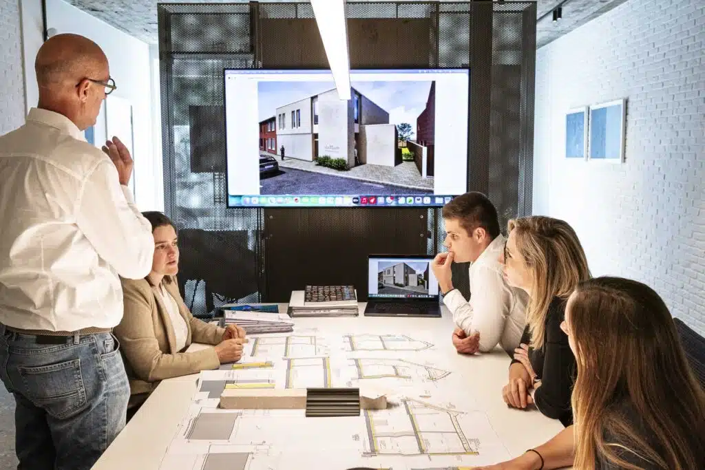 Architectenteam van ONA Architecten Beveren bespreekt bouwplannen en 3D-renders tijdens een projectvergadering