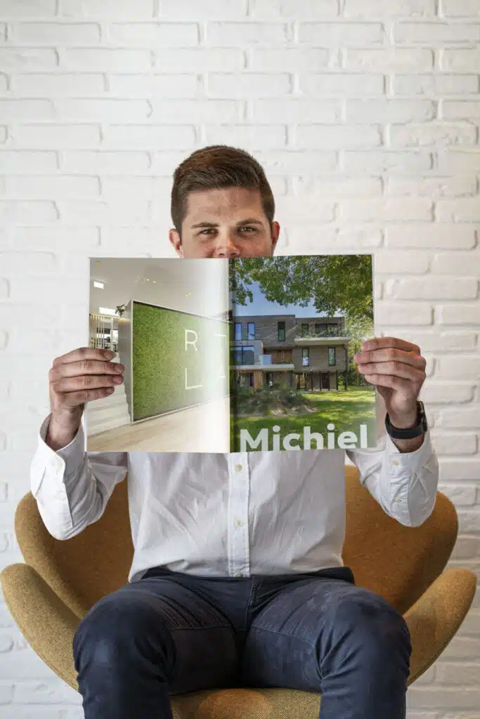 Michiel, architect bij ONA Architecten Beveren, houdt een magazine vast met een project van het bureau op de cover