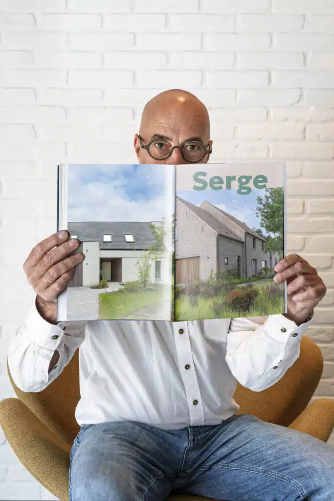 Serge Chiapparo, architect bij ONA Architecten Beveren, houdt een opengeslagen magazine met woningprojecten voor zijn