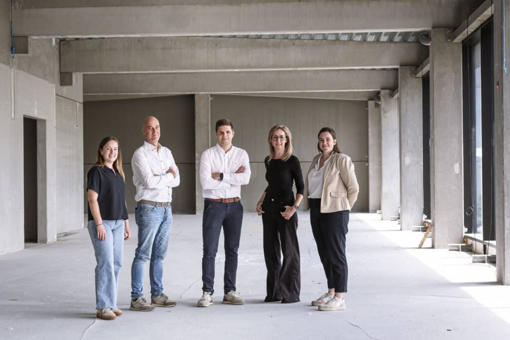 Het team van ONA Architecten in hun nieuwe kantoor in Beveren: vijf architecten poseren in een ruimte in afwerking.