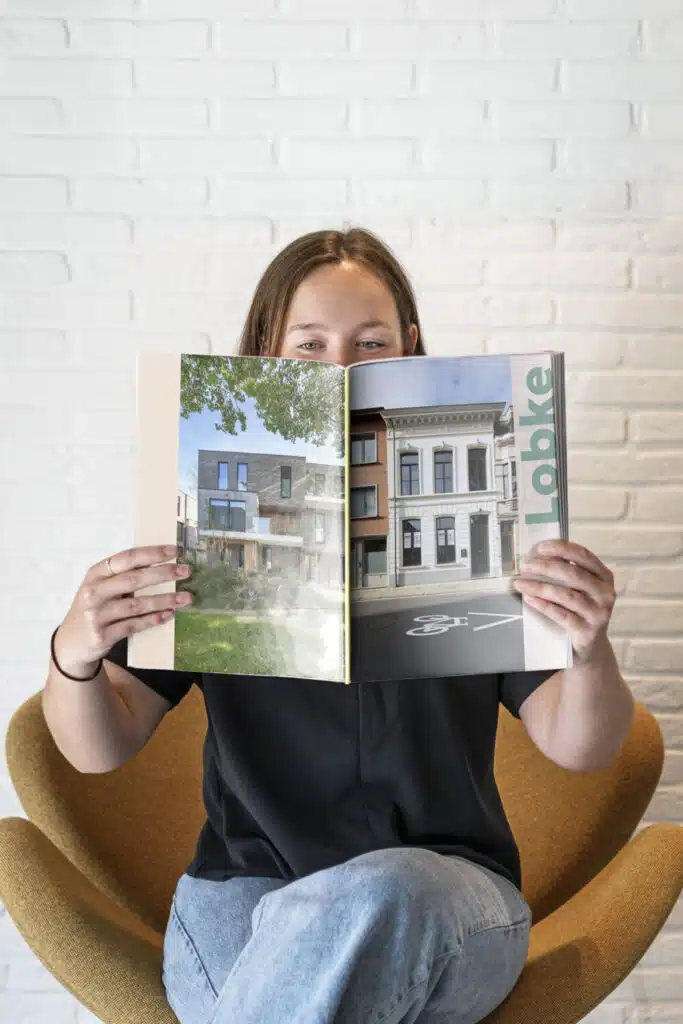 Lobke, architect bij ONA Architecten Beveren, leest een magazine met architectuurprojecten terwijl ze in een stoel zit